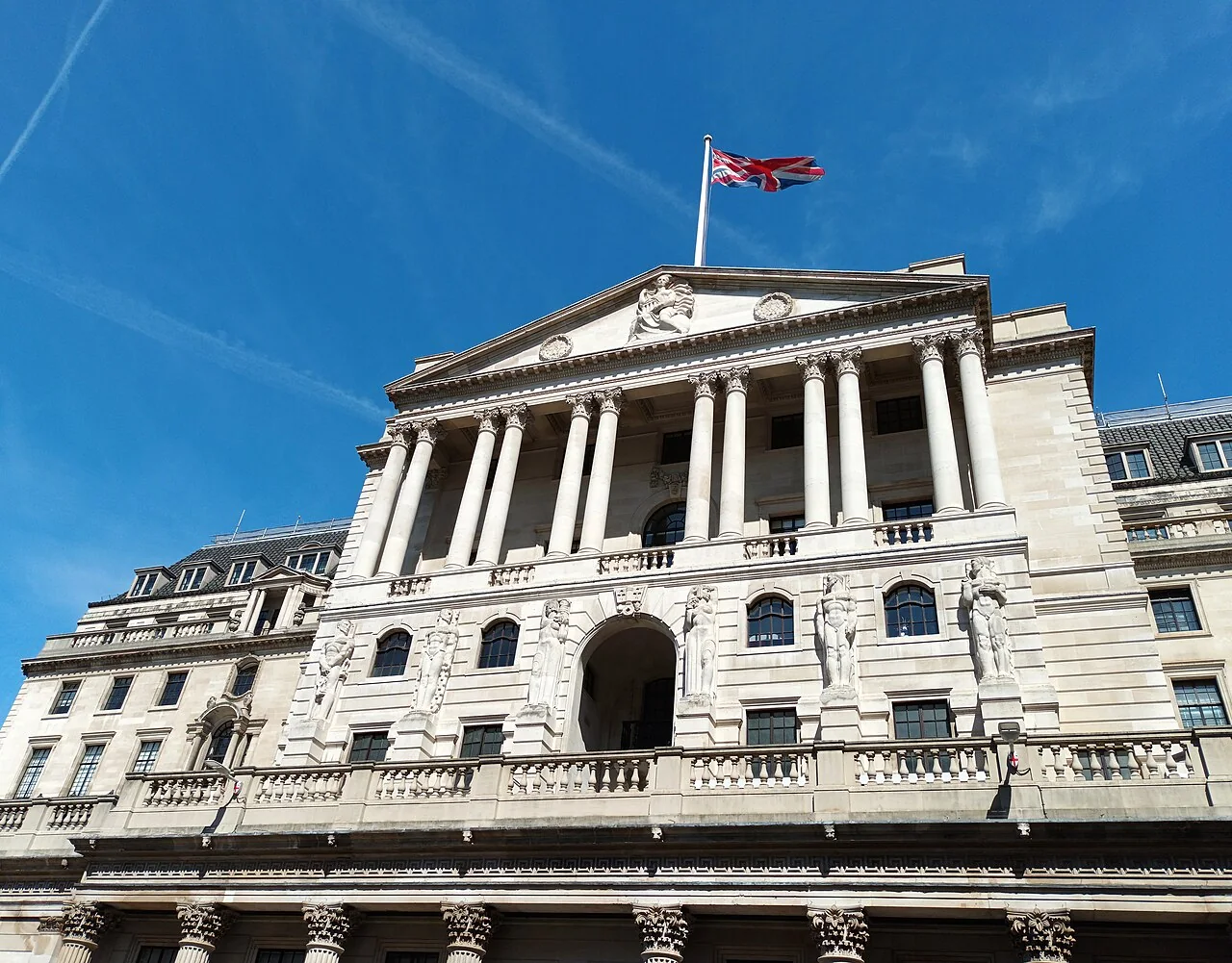 The Bank of England building in London under a blue sky.