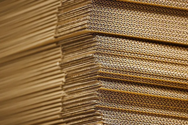 Stacks of flattened corrugated cardboard with their fluted edges visible.