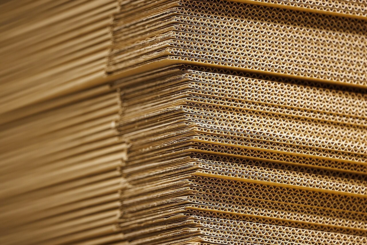 Stacks of flattened corrugated cardboard with their fluted edges visible.