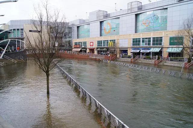 Floodwater beside shops and riverside walkways in Reading town centre.