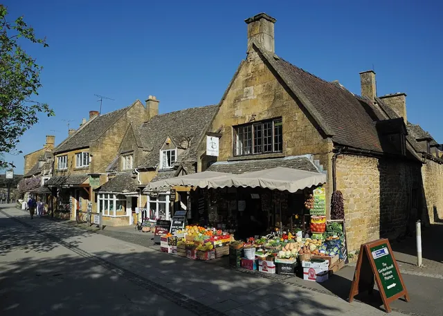Shops and an outdoor produce display on Broadway High Street in the Cotswolds.