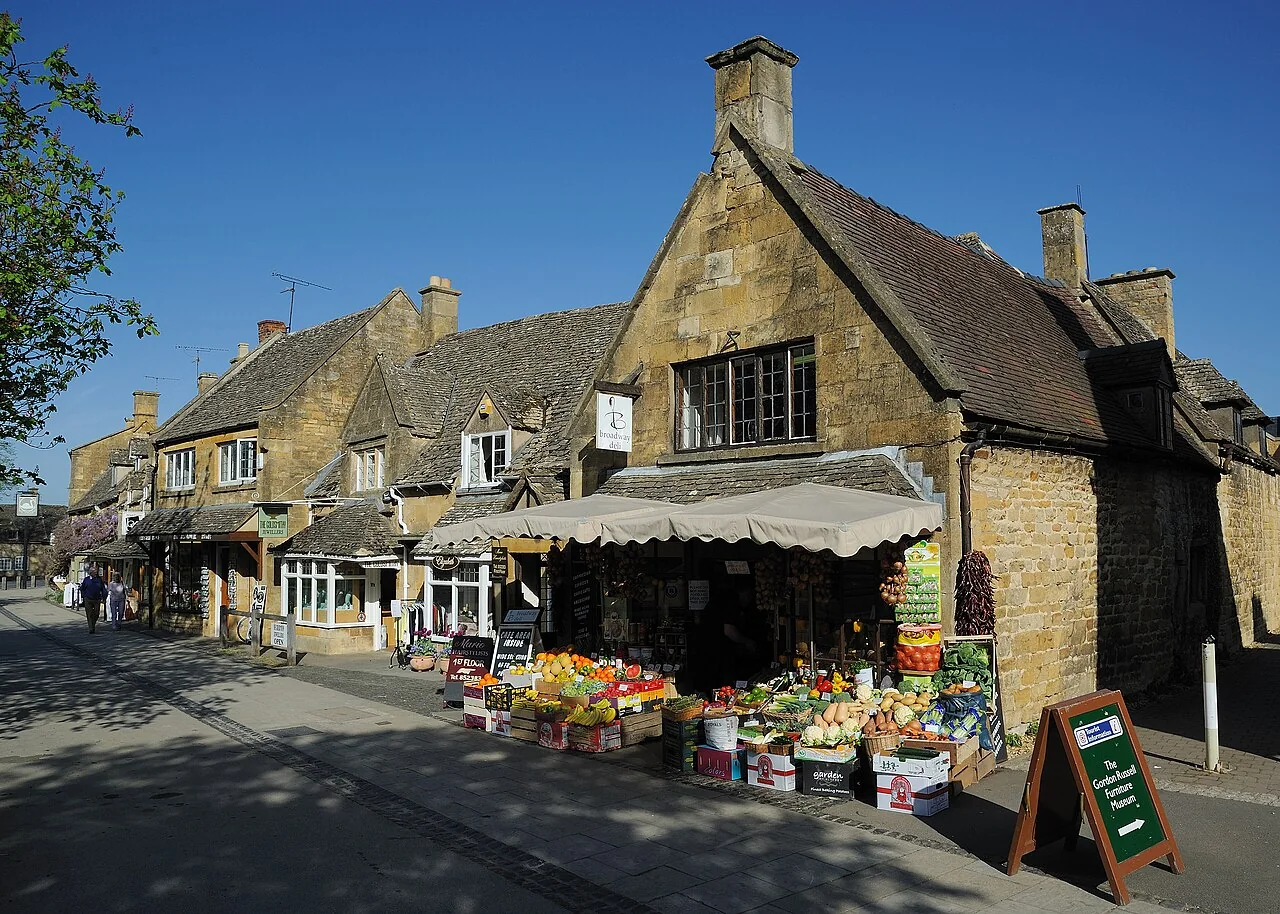 Shops and an outdoor produce display on Broadway High Street in the Cotswolds.