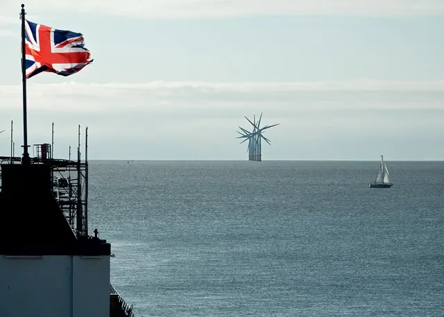 Offshore wind turbines at Gunfleet Sands, seen across the sea with a Union flag in the foreground.