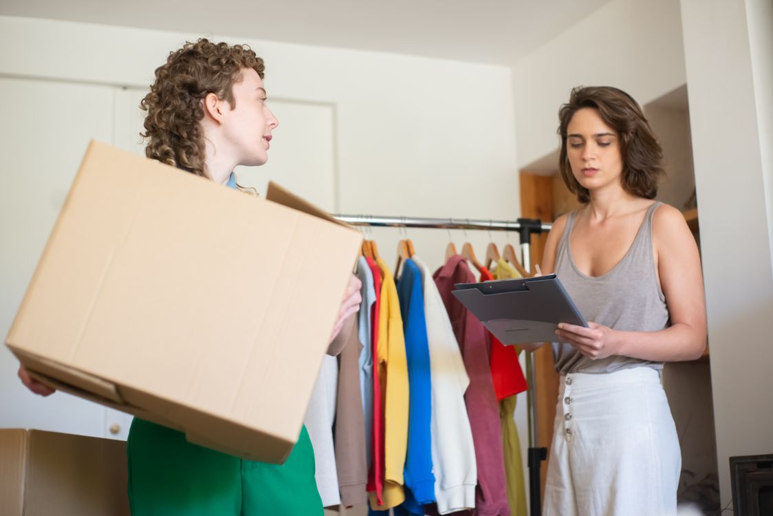 Two people organising clothing and packing an order in a small workspace