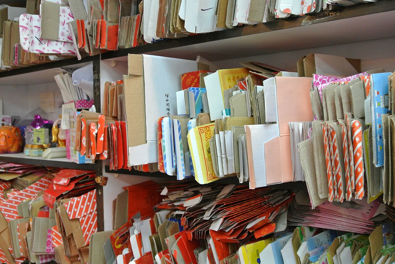 Shelves holding flattened cardboard gift boxes in several colours and sizes.