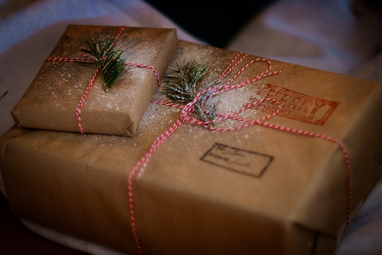 Holiday gifts wrapped in brown paper with twine and pine leaves.