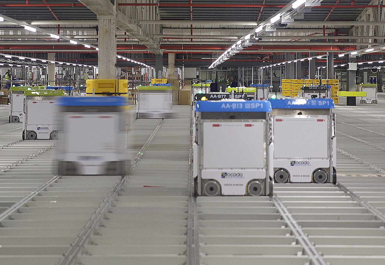 Robots moving across an automated Ocado warehouse grid.